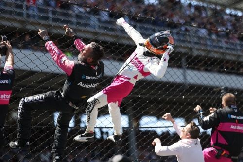 Hélio Castroneves klimt in de hekken na zijn Indianapolis 500 zege